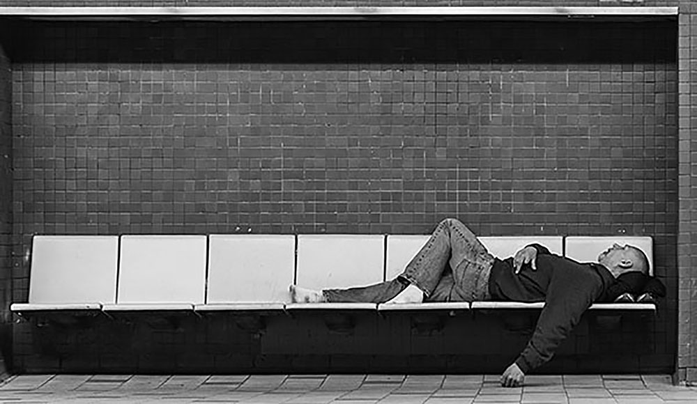 A homeless man seen sleeping on a row of seats in a Montreal subway station.